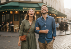 Un couple moderne marche et rit ensemble près d'un café parisien, partageant un moment de complicité spontané.